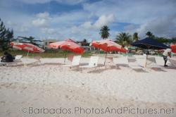 Red umbrellas and white beach chairs at Carlisle Bay Beach in Bridgetown Barbados.jpg
